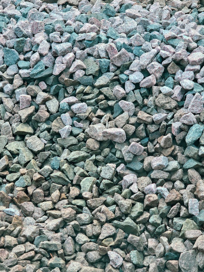 Close-up view of natural stones and pebbles forming a textured background, showcasing erosion and variation in color.